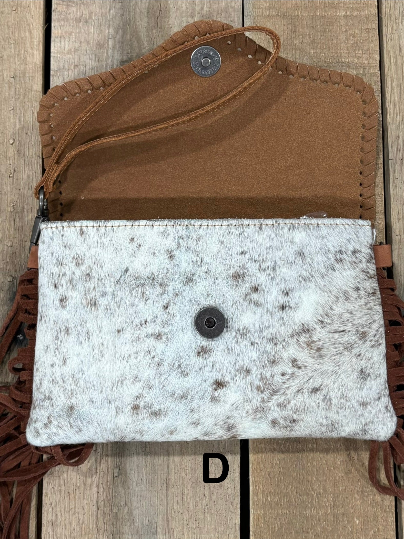 Brown tooled leather and cowhide bag with side fringe. This bag has both a wristlet and should strap. Front View
