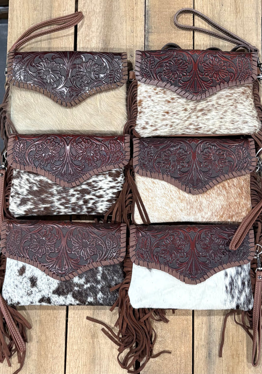 Six crossbody leather handbags with cowhide patterns on a wooden surface