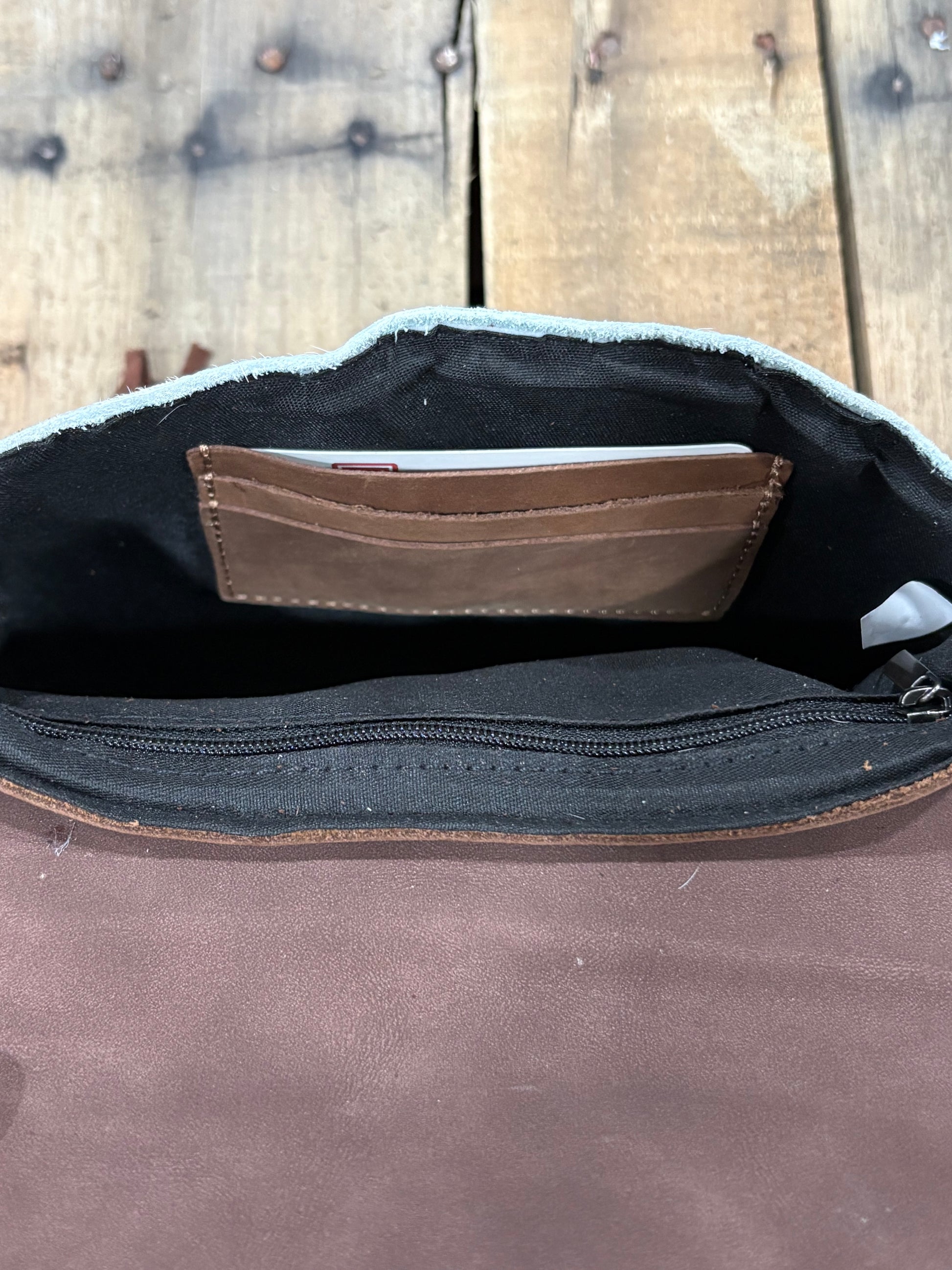 Card slot view of a Coffee Brown leather bag with open compartment showing a brown wallet on a wooden surface