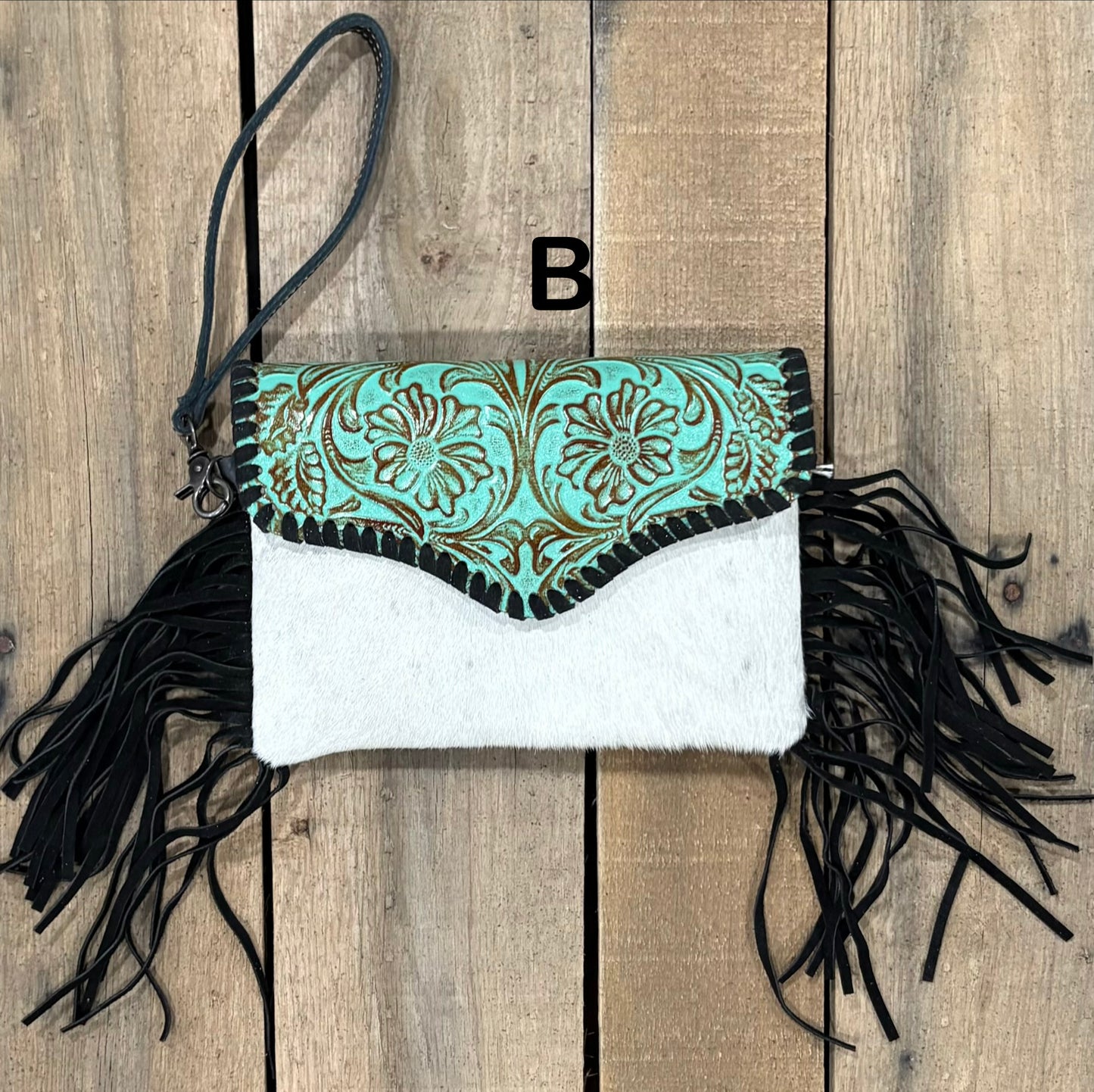 Turquoise tooled leather and cowhide bag with side fringe. This bag has both a wristlet and should strap. Front View