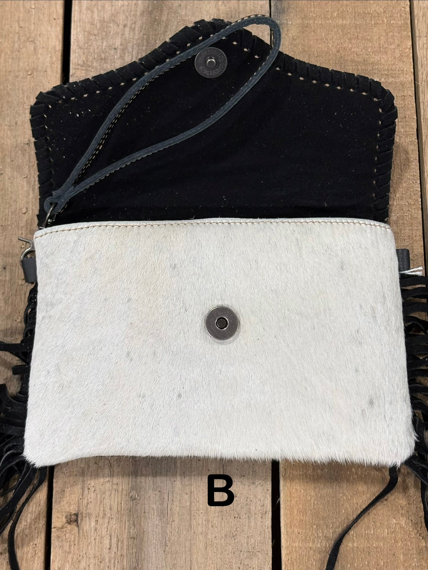 Turquoise tooled leather and cowhide bag with side fringe. This bag has both a wristlet and should strap. Front View