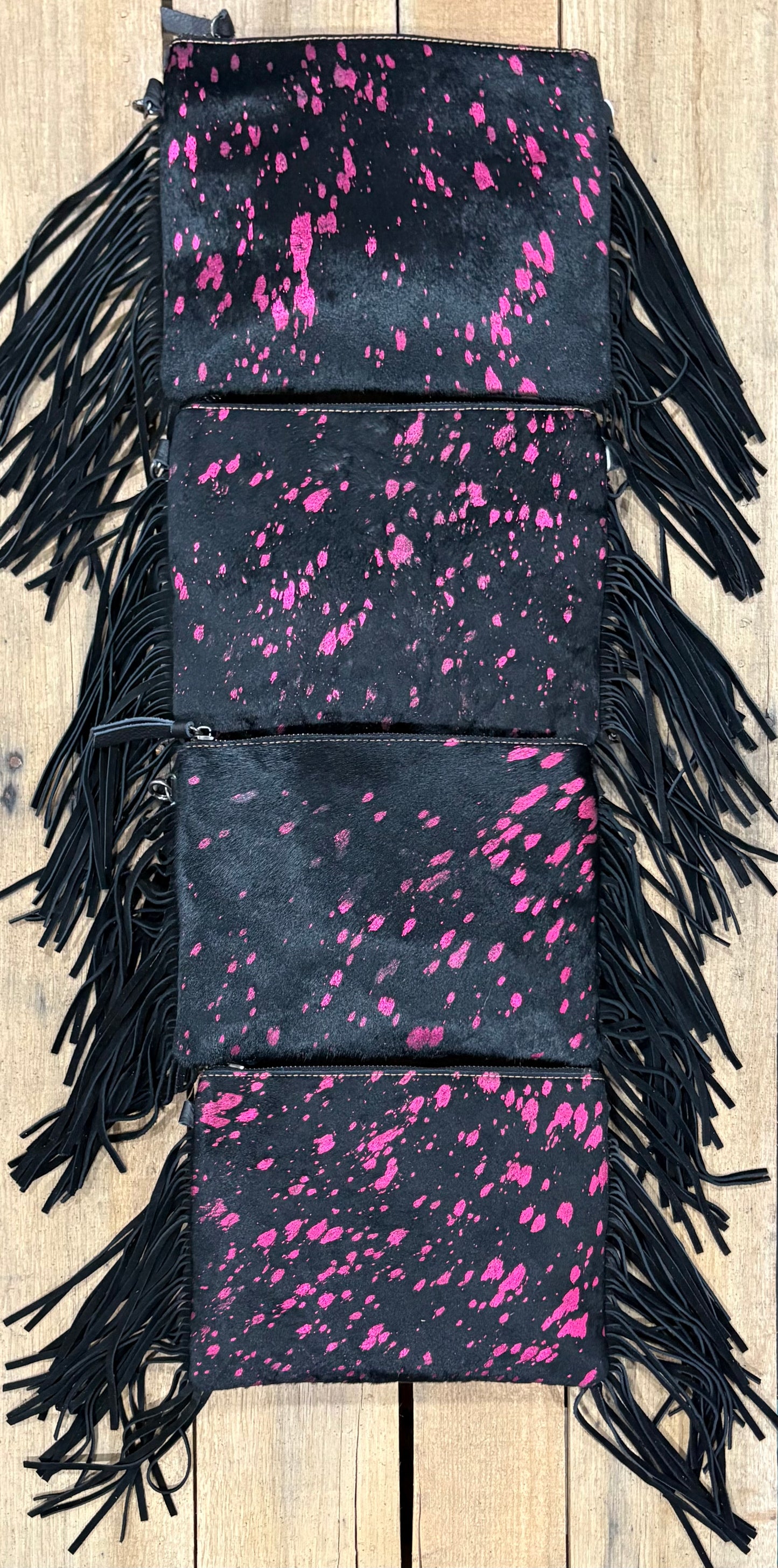 Four purse view of Pink and black hairon crossbodys on a wooden background