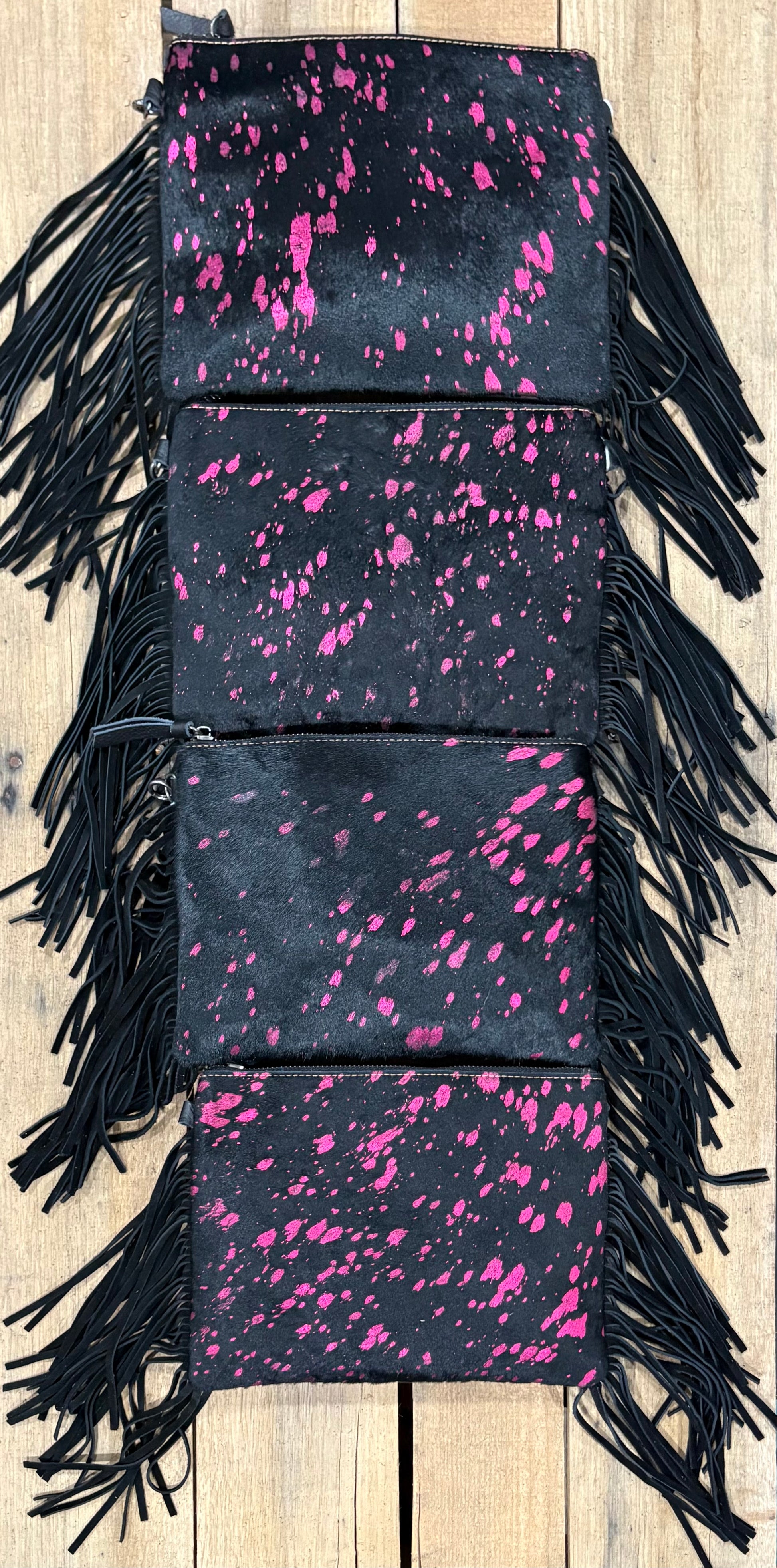 Four purse view of Pink and black hairon crossbodys on a wooden background