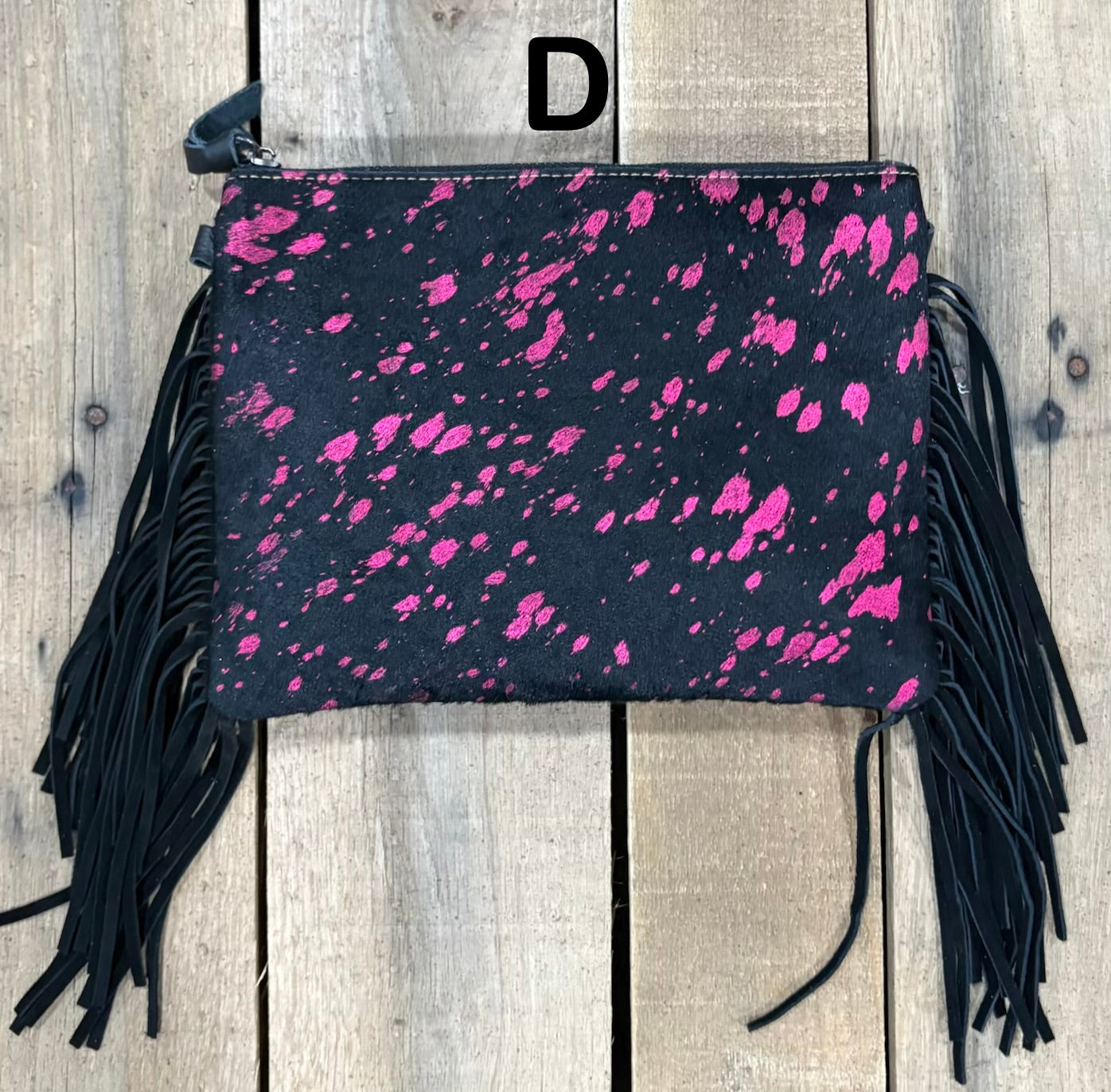 Black clutch with pink speckles and black hairon fringe on a wooden surface