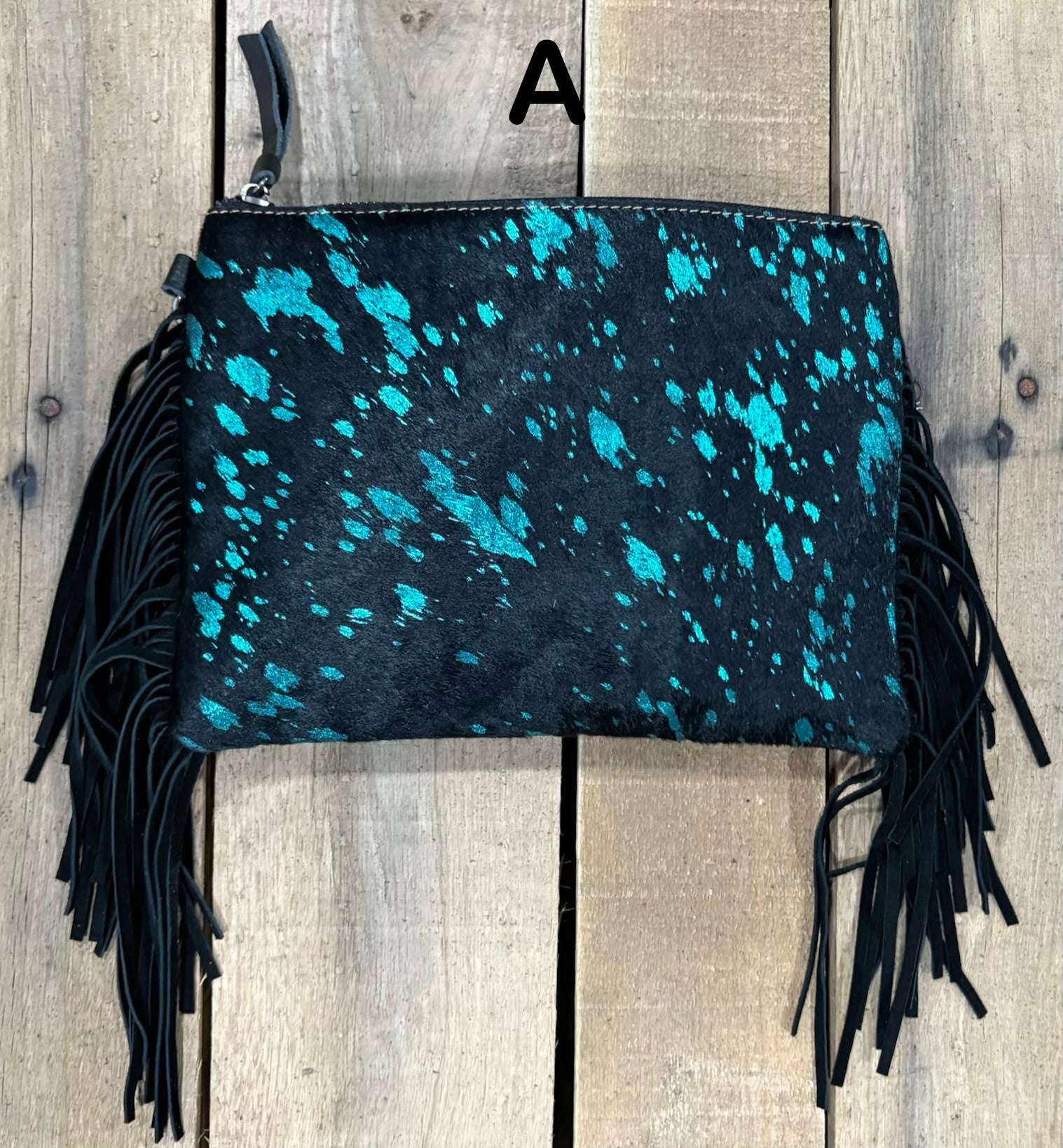 Black clutch with pink speckles and black hairon fringe on a wooden surface