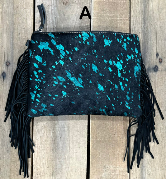 Black clutch with pink speckles and black hairon fringe on a wooden surface