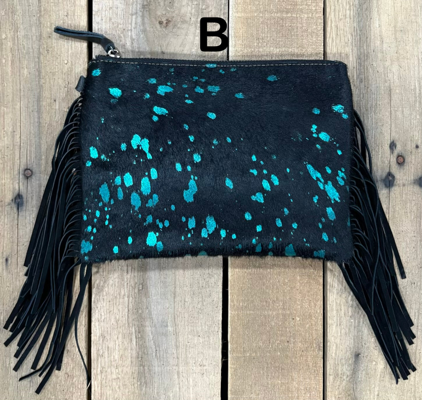 Black clutch with pink speckles and black hairon fringe on a wooden surface