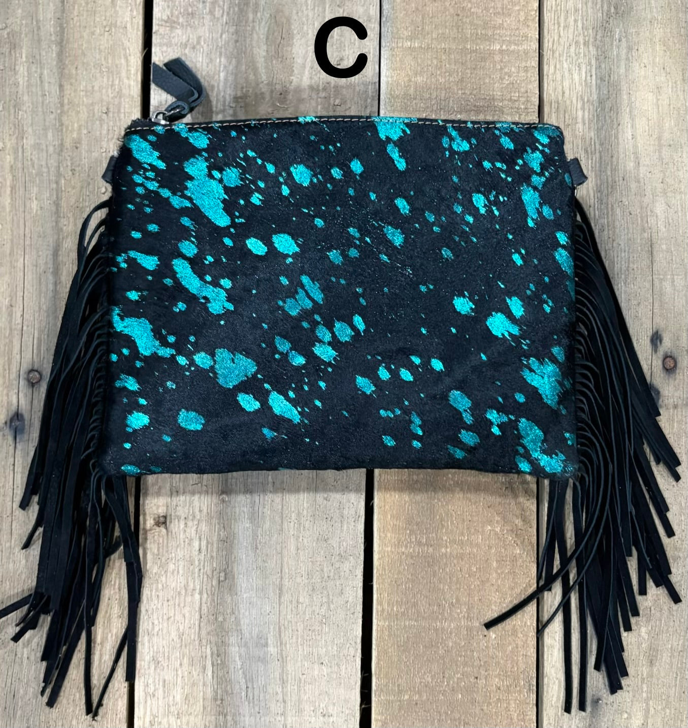 Black clutch with pink speckles and black hairon fringe on a wooden surface