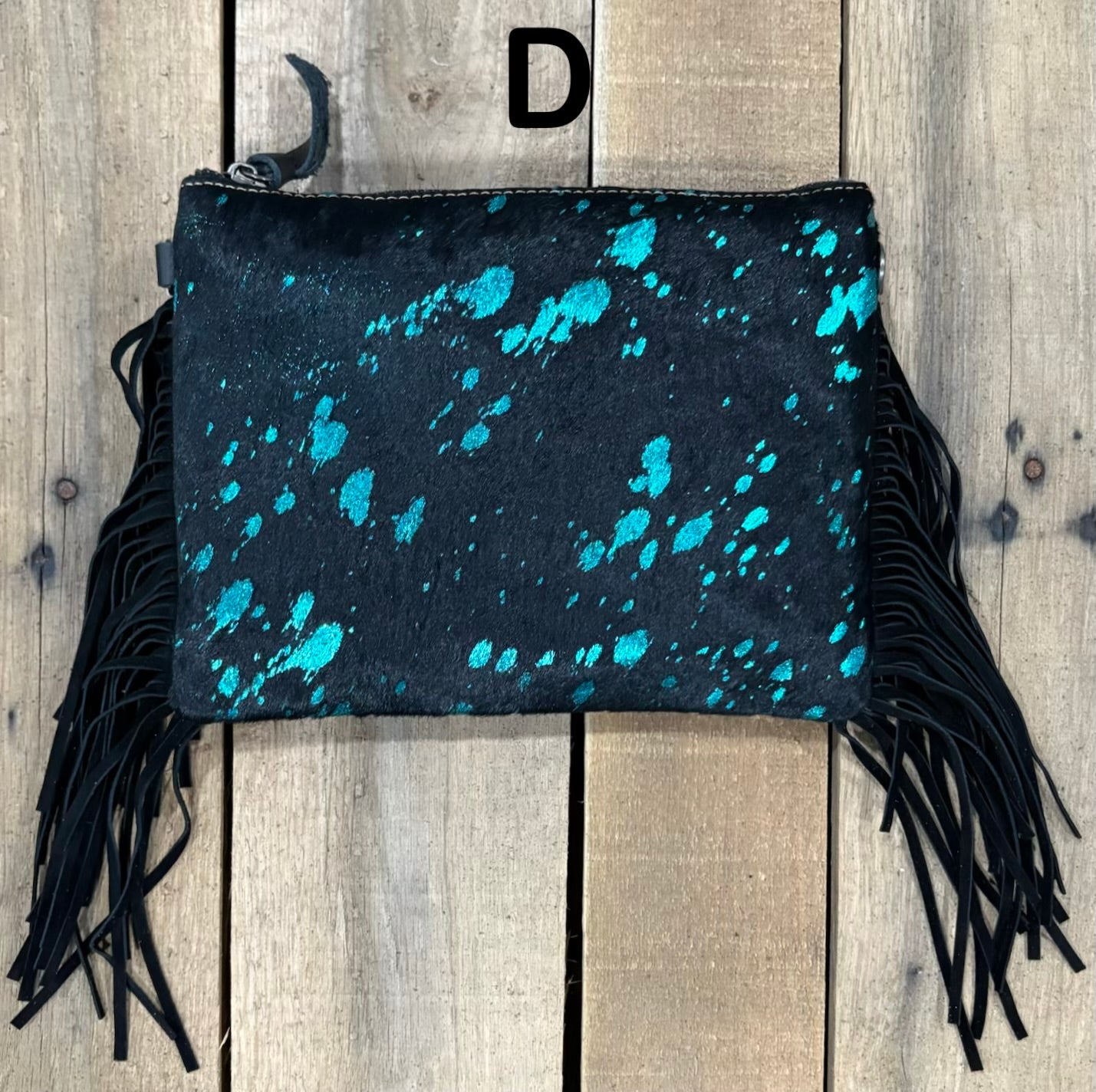 Black clutch with pink speckles and black hairon fringe on a wooden surface