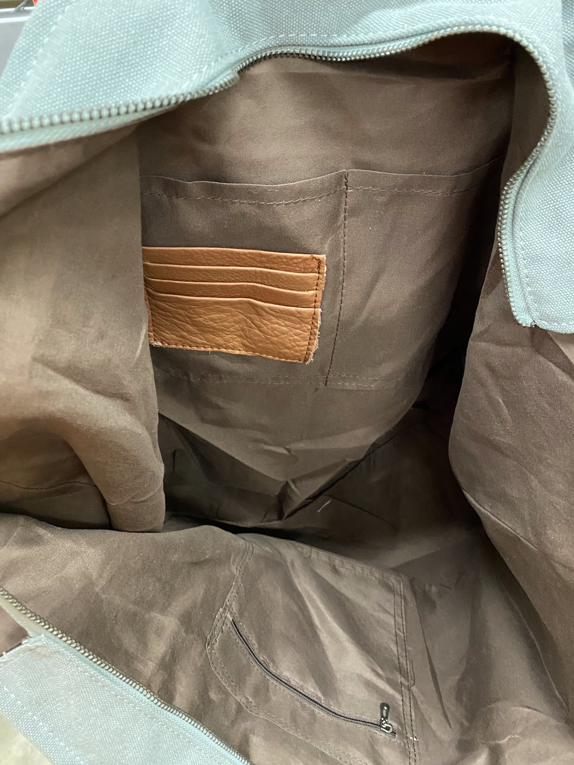Close-up of a brown fabric inside with a leather credit cards holder and multiple pockets.