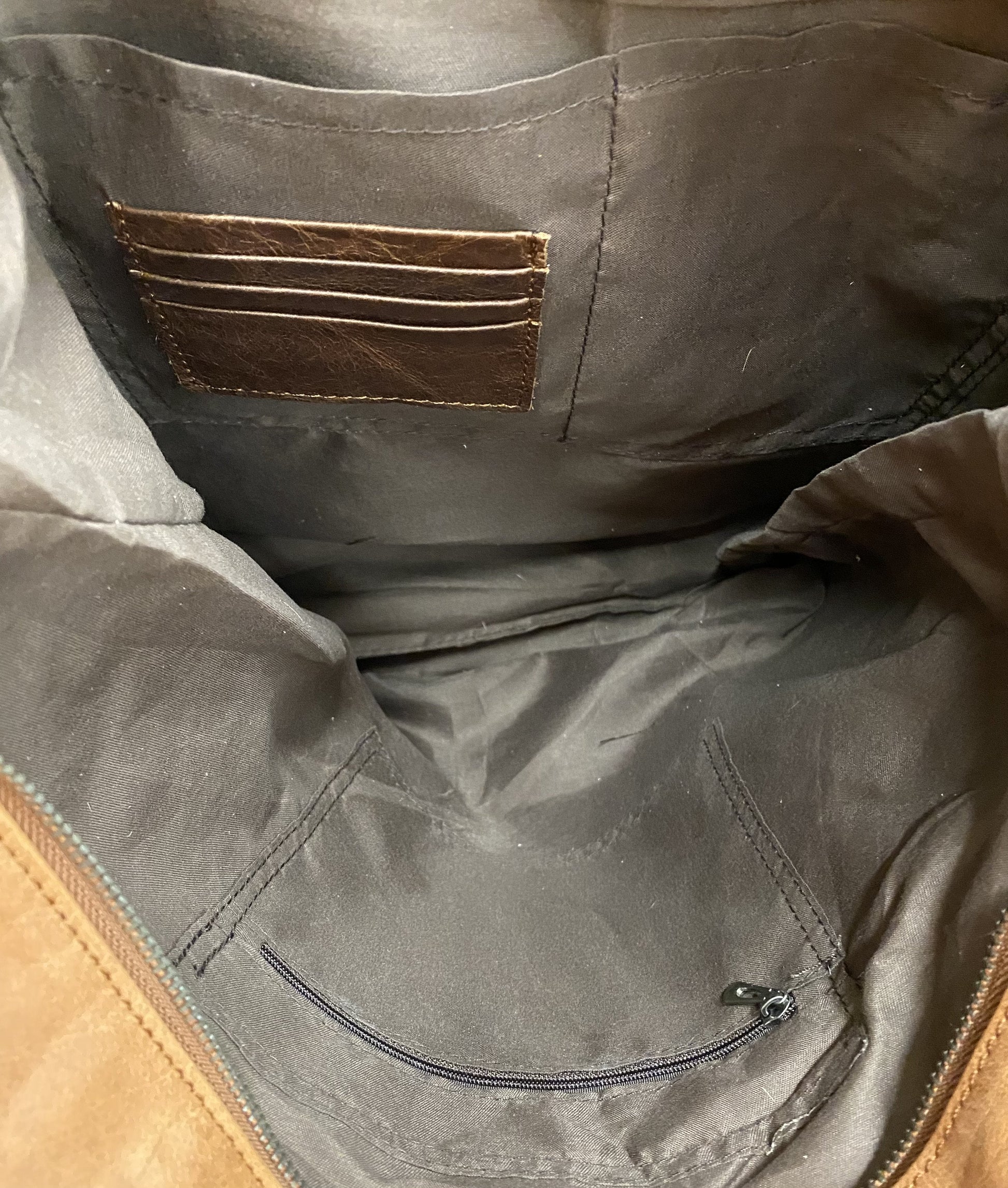 This Brown leather and cowhide tote features a concealed carry pocket as on the solid leather back. Inside view showing three card slots, a zippered closed pocket and two additional pockets. 
