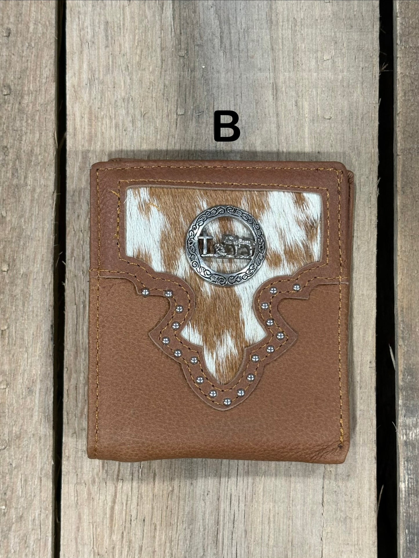 Brown leather wallet with white cowhide pattern and praying cowboy concho on a wooden surface