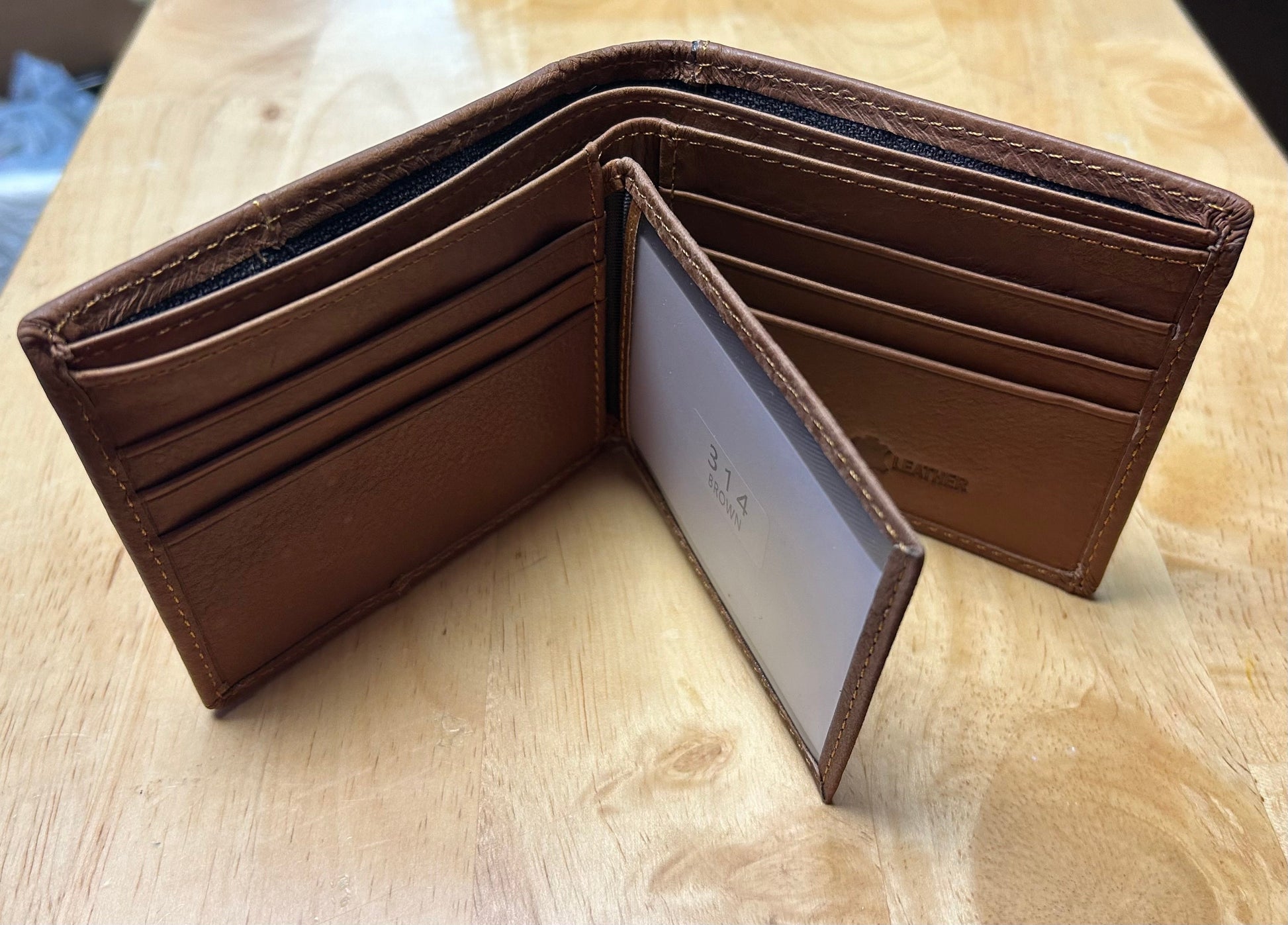 Brown leather wallet open on a wooden surface