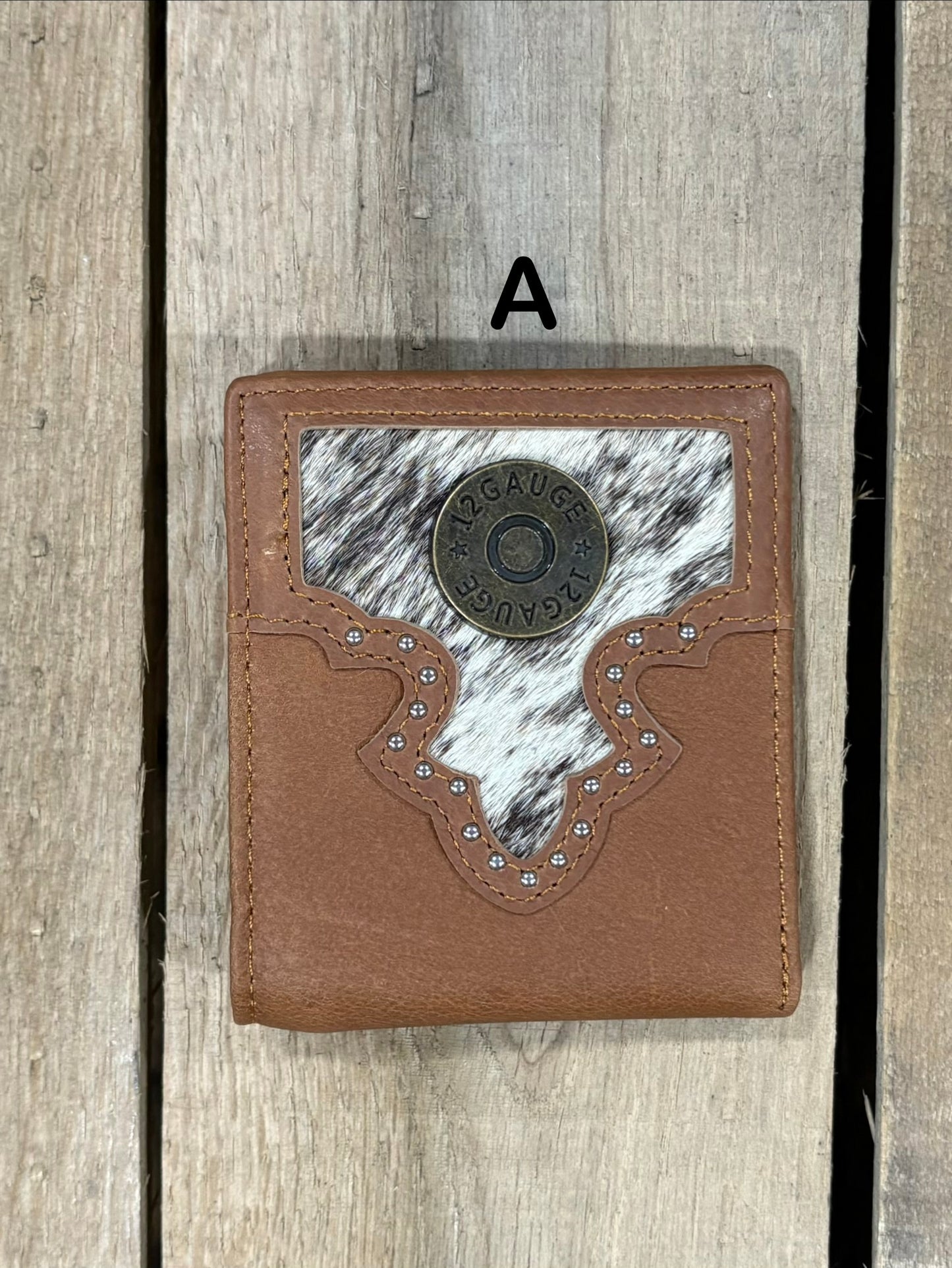 Brown leather wallet with white cowhide pattern and shotgun shell concho on a wooden surface