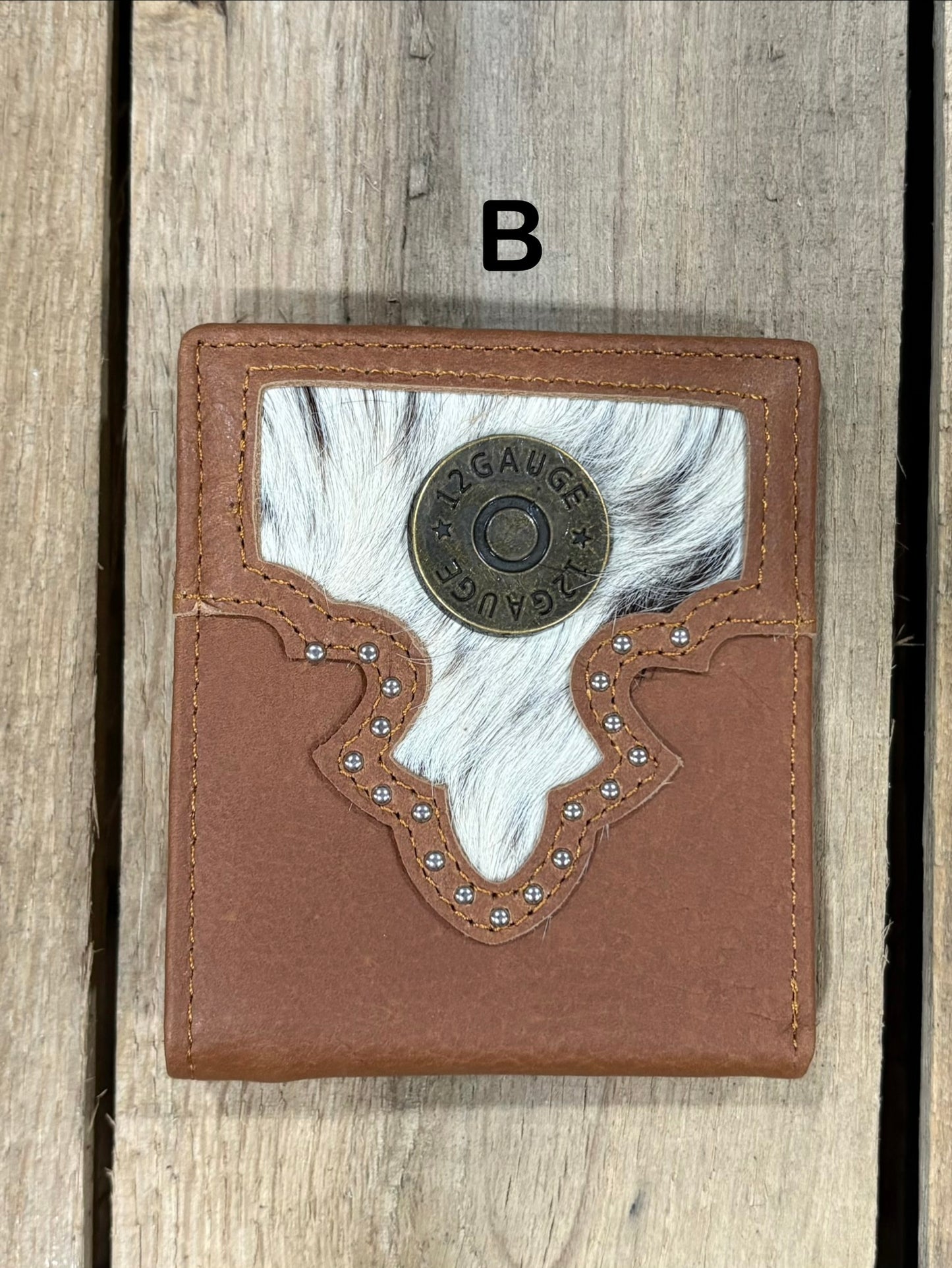 Brown leather wallet with white cowhide pattern and shotgun shell concho on a wooden surface
