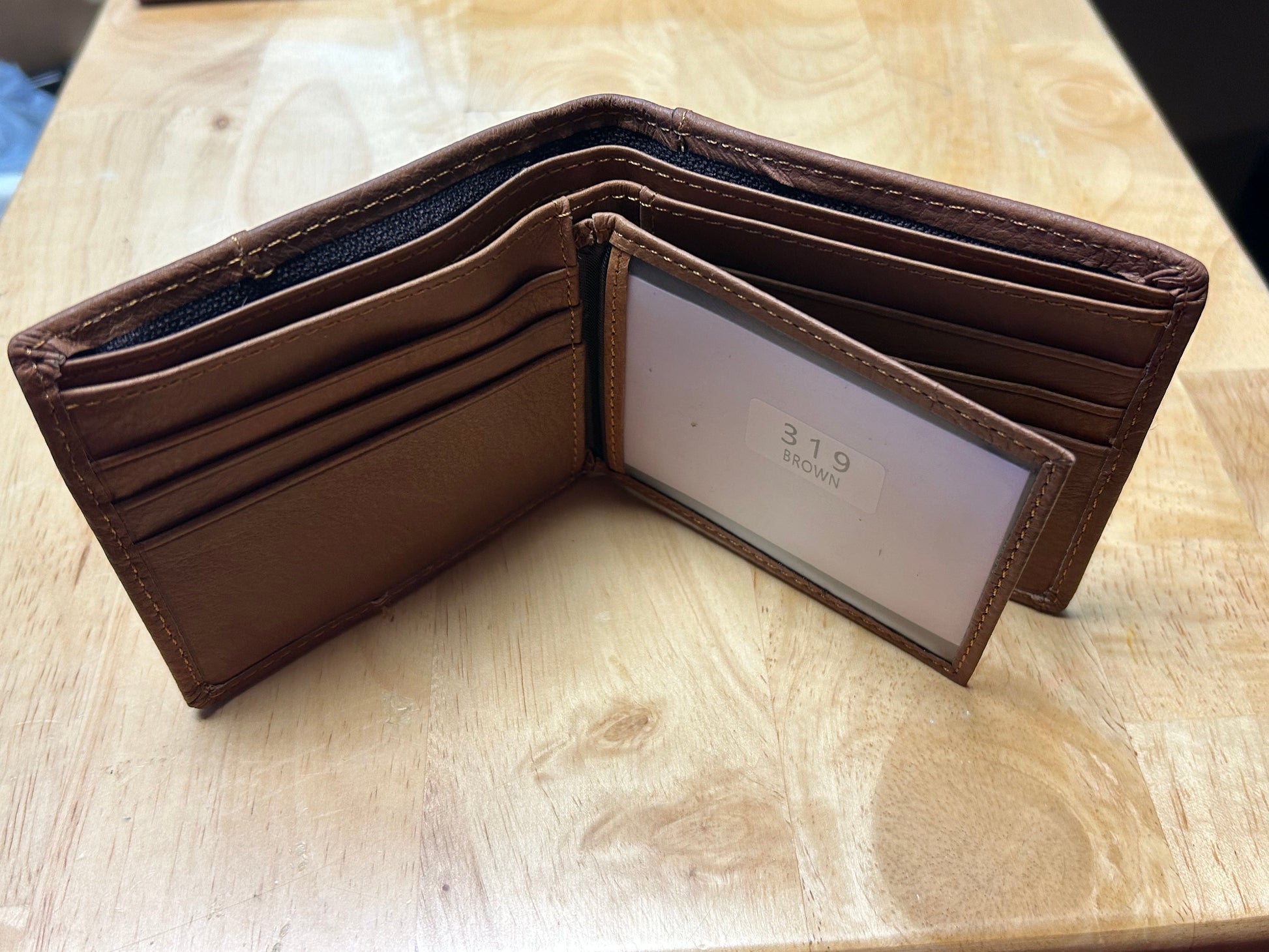 Brown leather wallet with '319' branding on a wooden surface