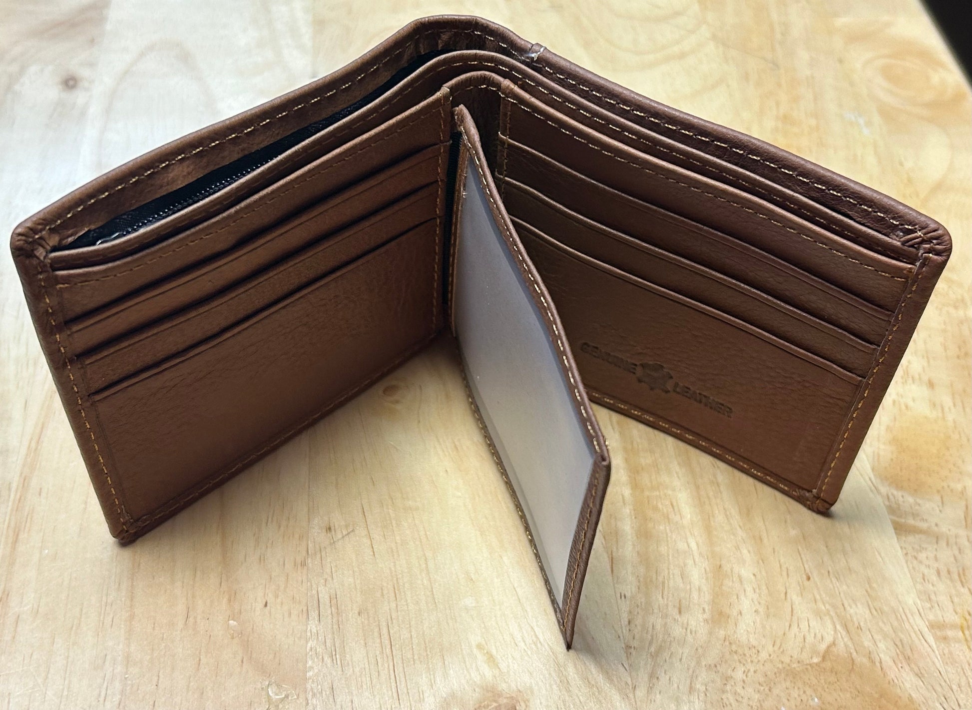 Brown leather wallet open on a light wooden surface