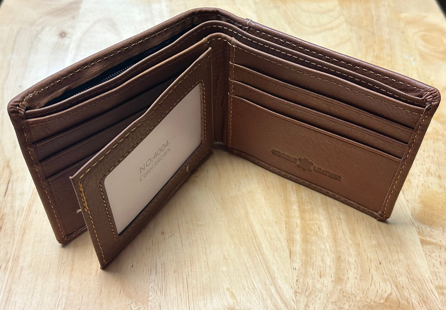 Brown leather wallet with visible brand name on a light wooden surface