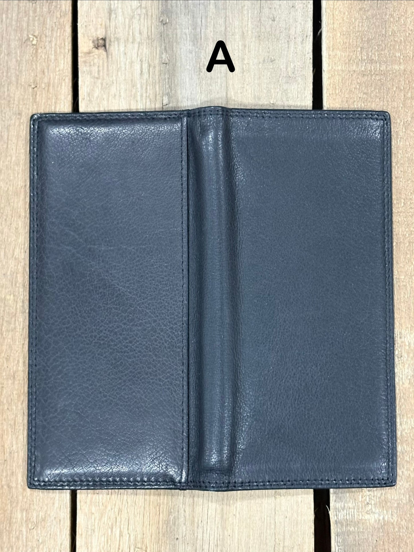 Black leather tall wallet on a wooden surface