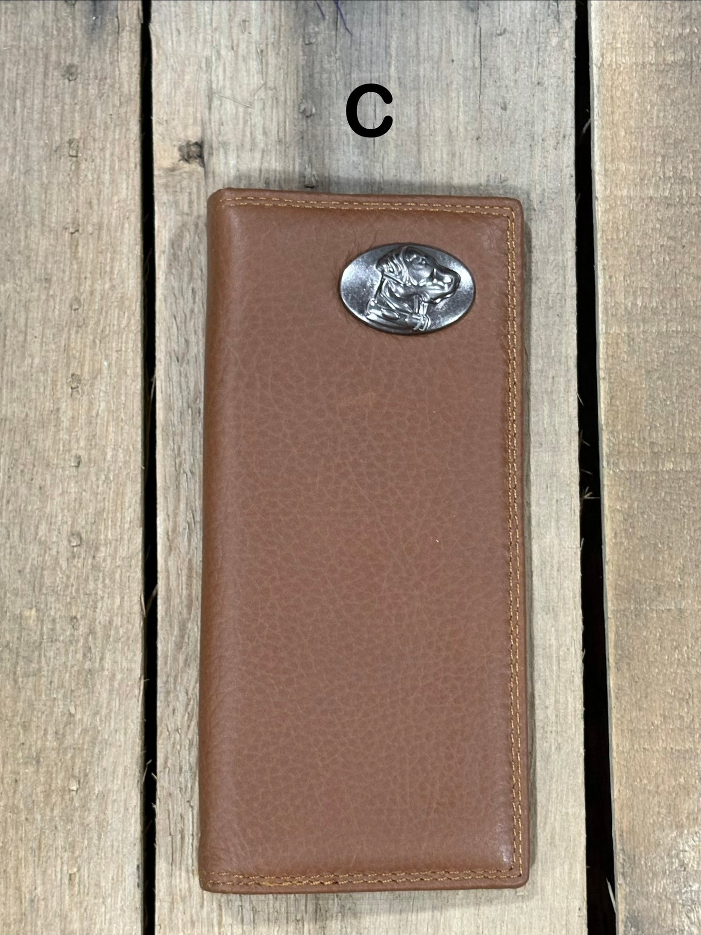 Brown leather wallet with a lab head silver concho on a wooden surface