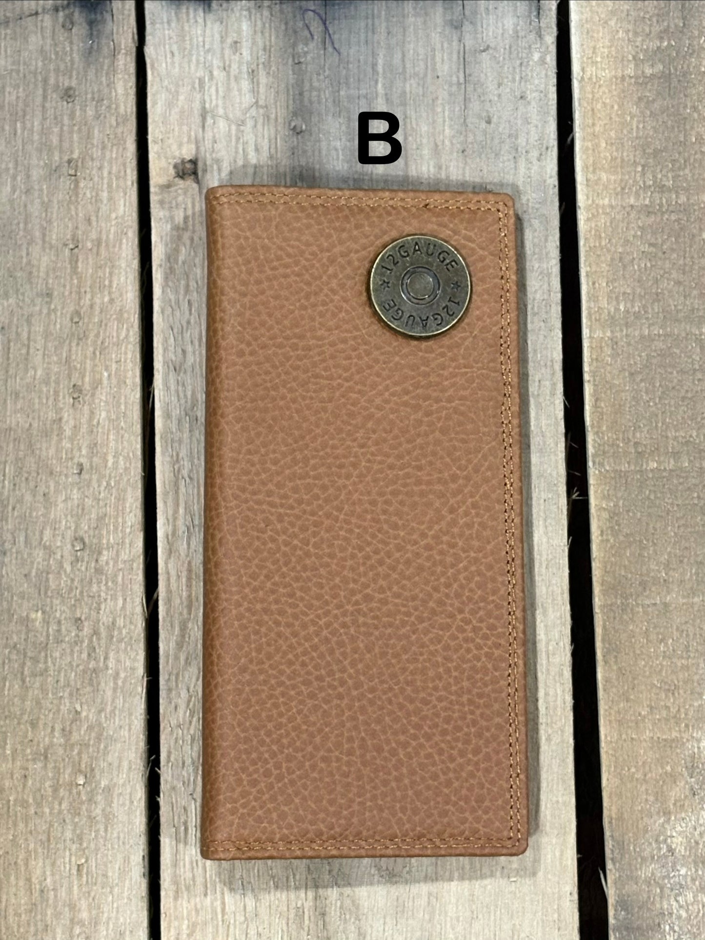 Brown leather wallet with a shotgun shell concho on a wooden surface