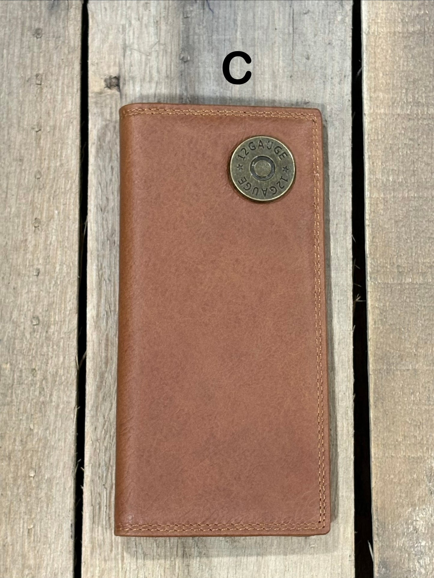 Brown leather wallet with a shotgun shell concho on a wooden surface