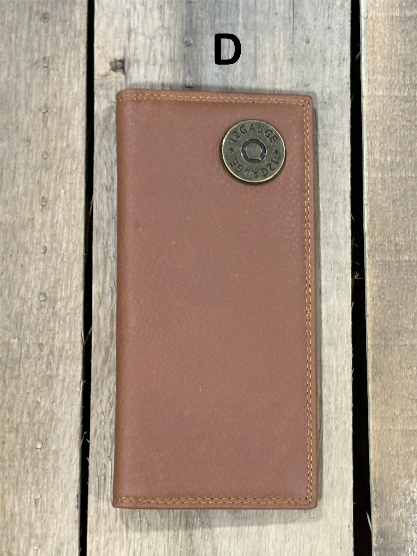Brown leather wallet with a shotgun shell concho on a wooden surface
