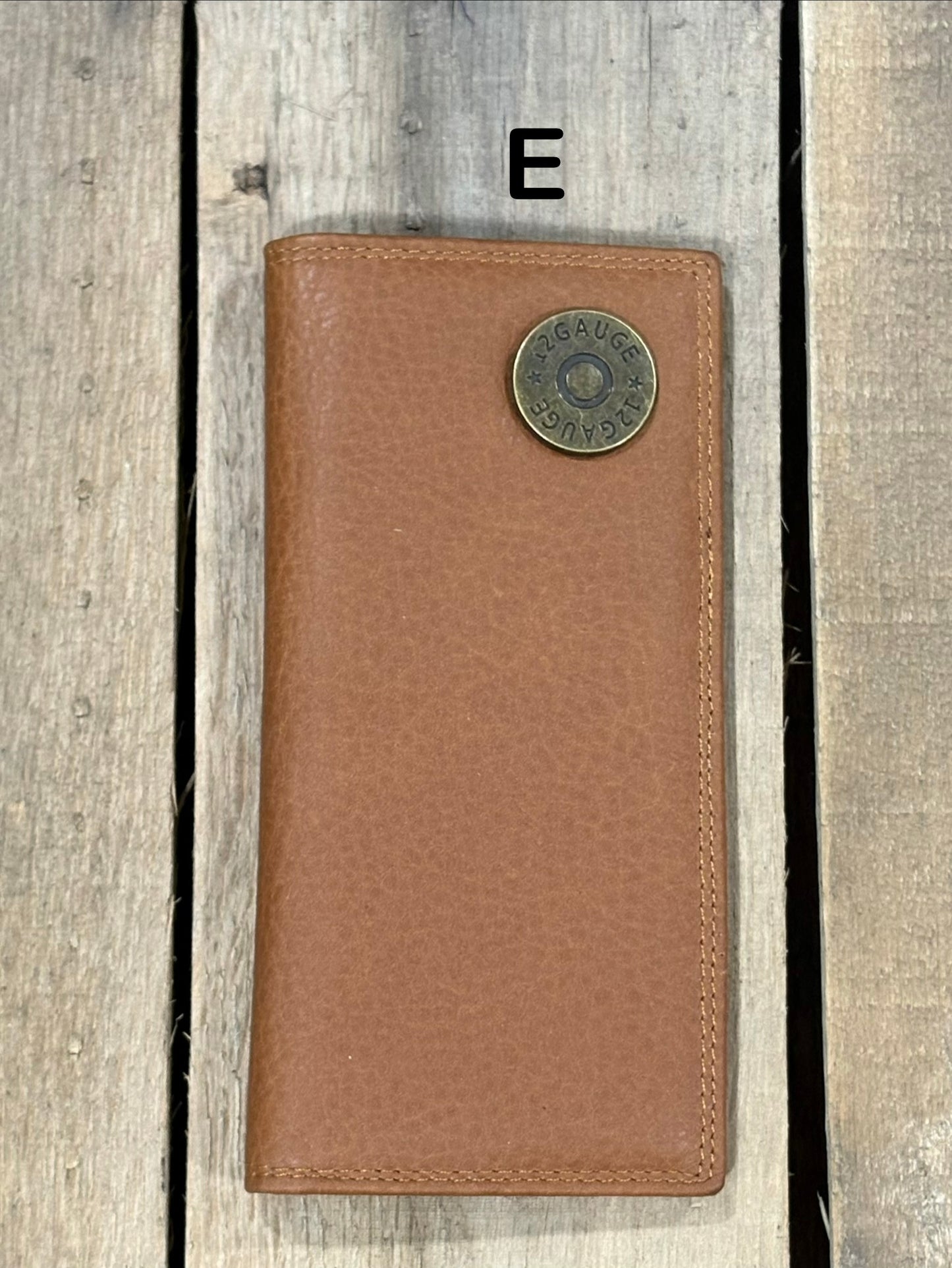 Brown leather wallet with a shotgun shell concho on a wooden surface