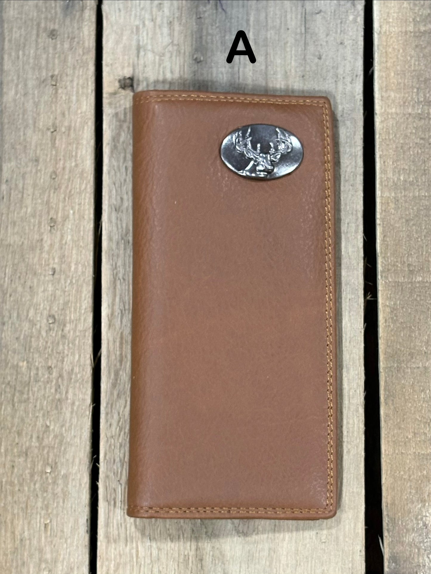 Brown leather wallet with a deer head concho on a wooden surface