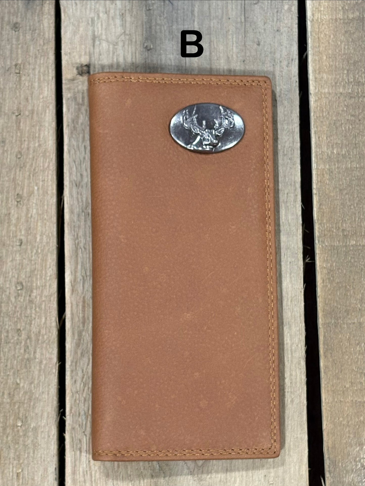 Brown leather wallet with a deer head concho on a wooden surface
