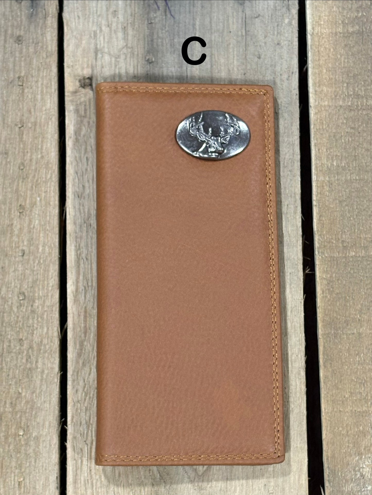 Brown leather wallet with a deer head concho on a wooden surface