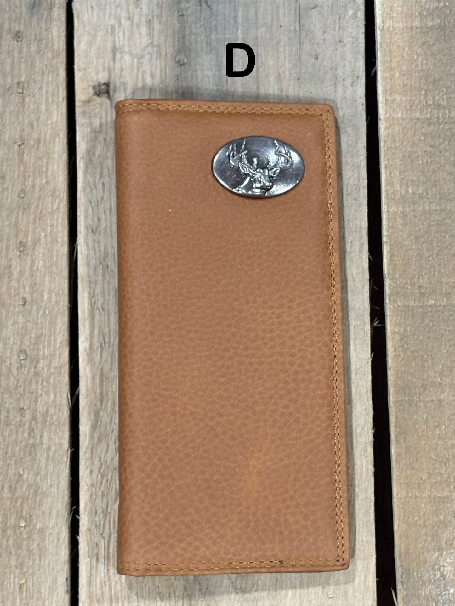 Brown leather wallet with a deer head concho on a wooden surface