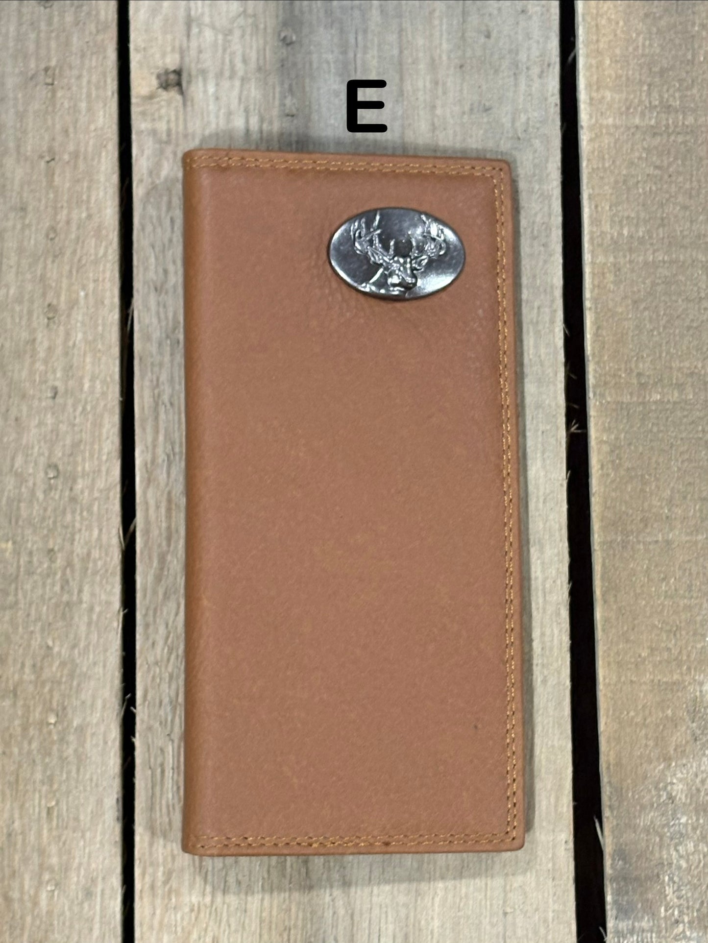 Brown leather wallet with a deer head concho on a wooden surface