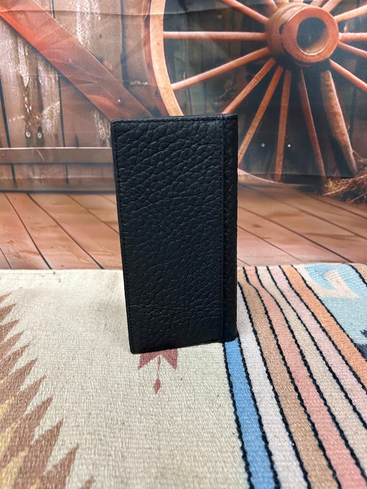 Black textured wallet on a patterned rug with a wooden wheel in the background
