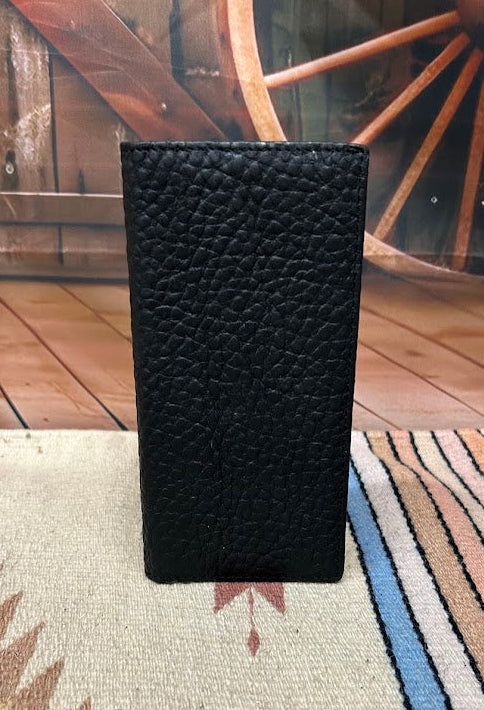 Black textured wallet on a patterned rug with wooden wheels in the background