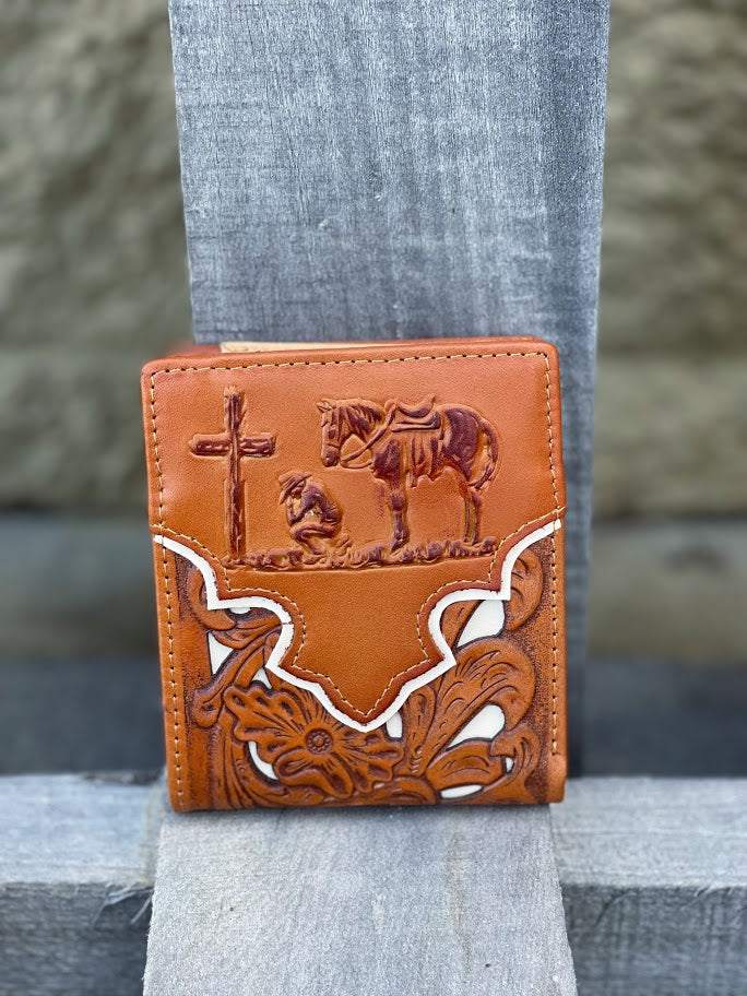 A light brown bifold leather wallet with a beige inlay design and a praying cowboy design. Front View