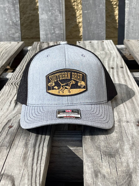 Gray and black cap with 'Southern Bred' logo on a wooden surface