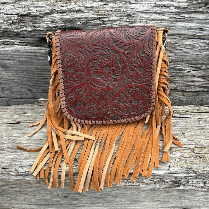 This Brown embossed leather crossbody bag features fringe sounds and it has a removable and adjustable should strap. This bag has a front flap and a zippered closed back pocket. It measures 6 inches tall, 6 1/4 inches wide and is 1 /12 inches deep.