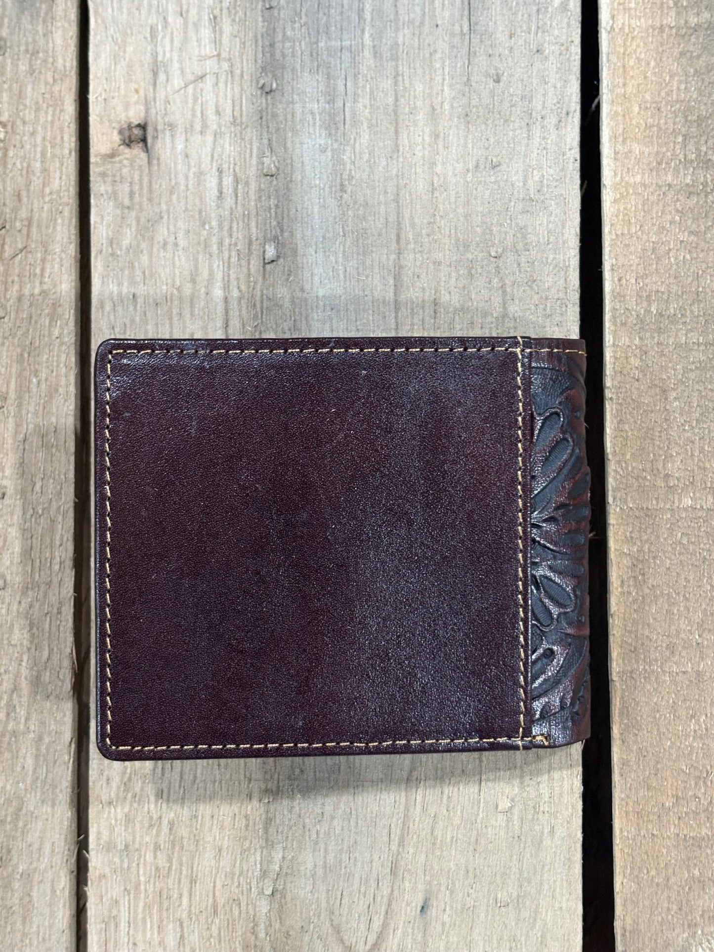 Coffee Brown leather wallet with floral embossing on a wooden surface