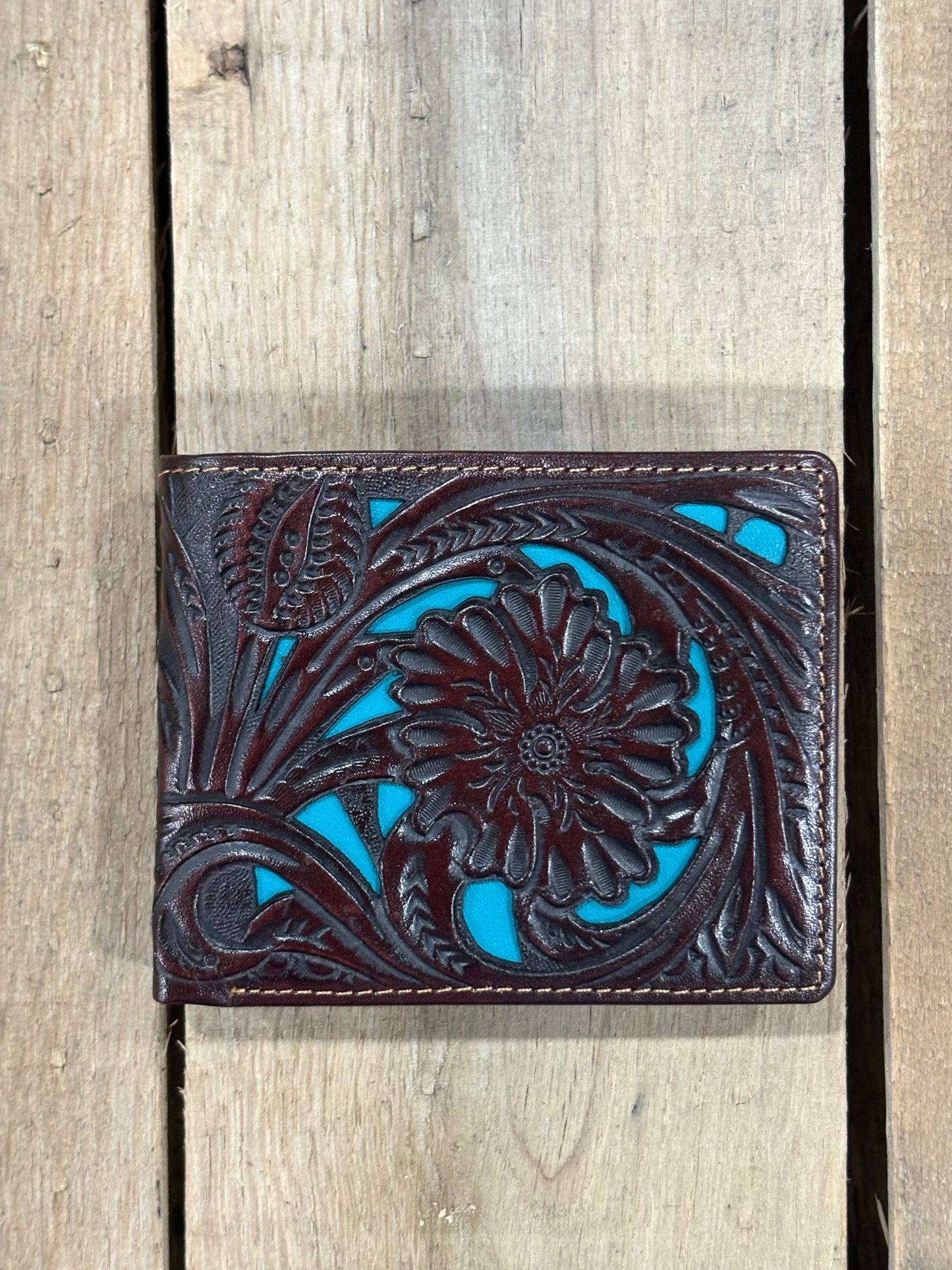 Coffee Brown leather wallet with floral design and turquoise inlay on a wooden background