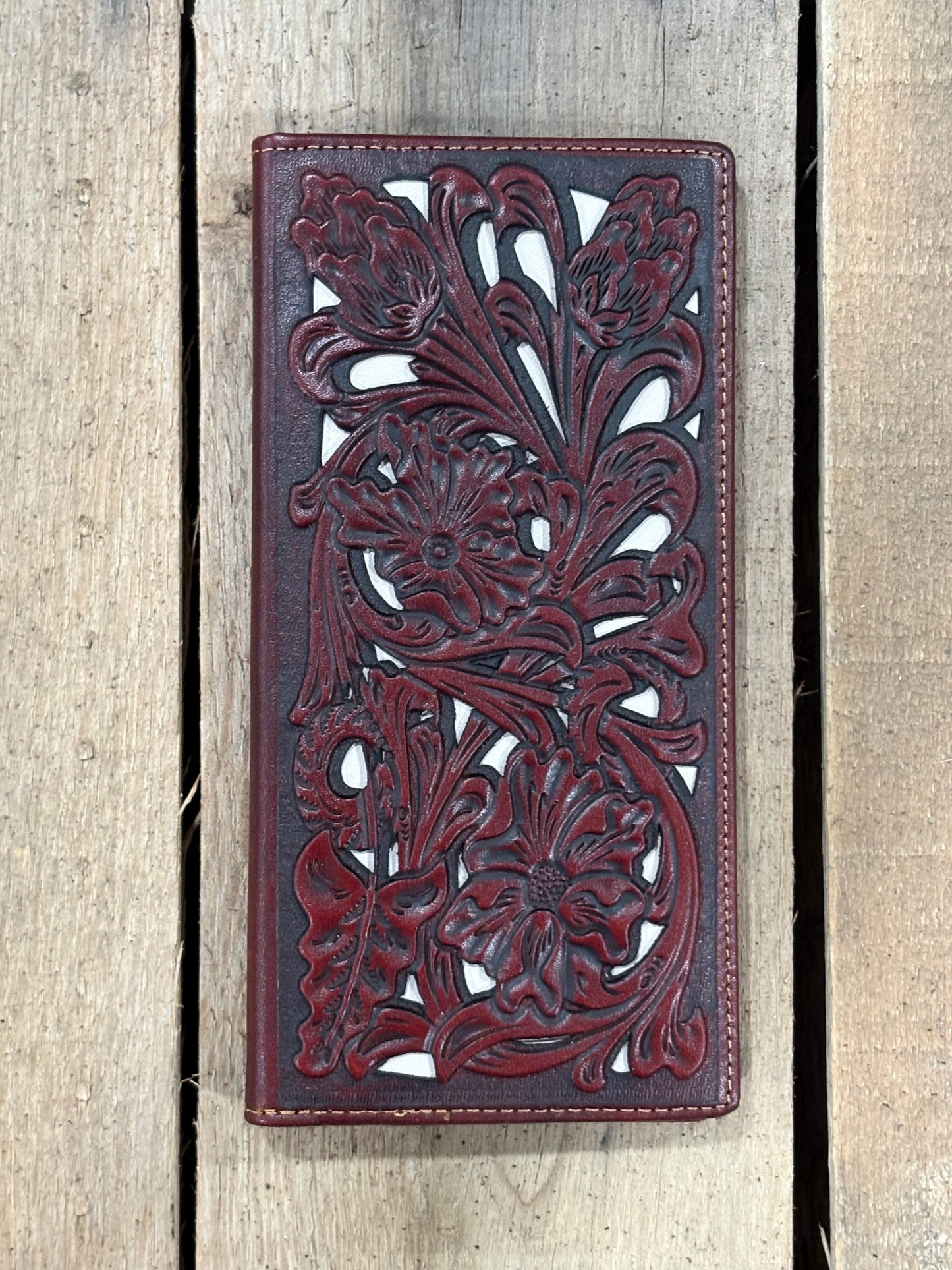 Brown leather wallet with intricate floral turquoise inlay designs on a wooden surface
