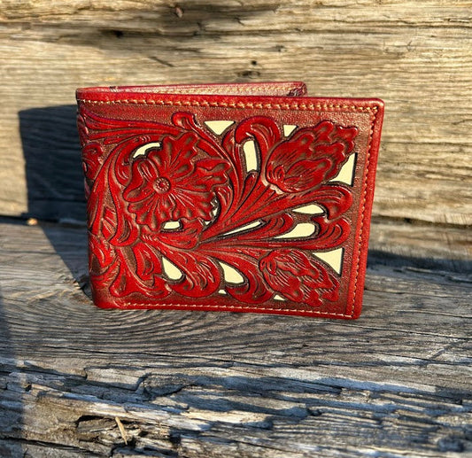 Brown leather wallet with floral tooling on a wooden surface