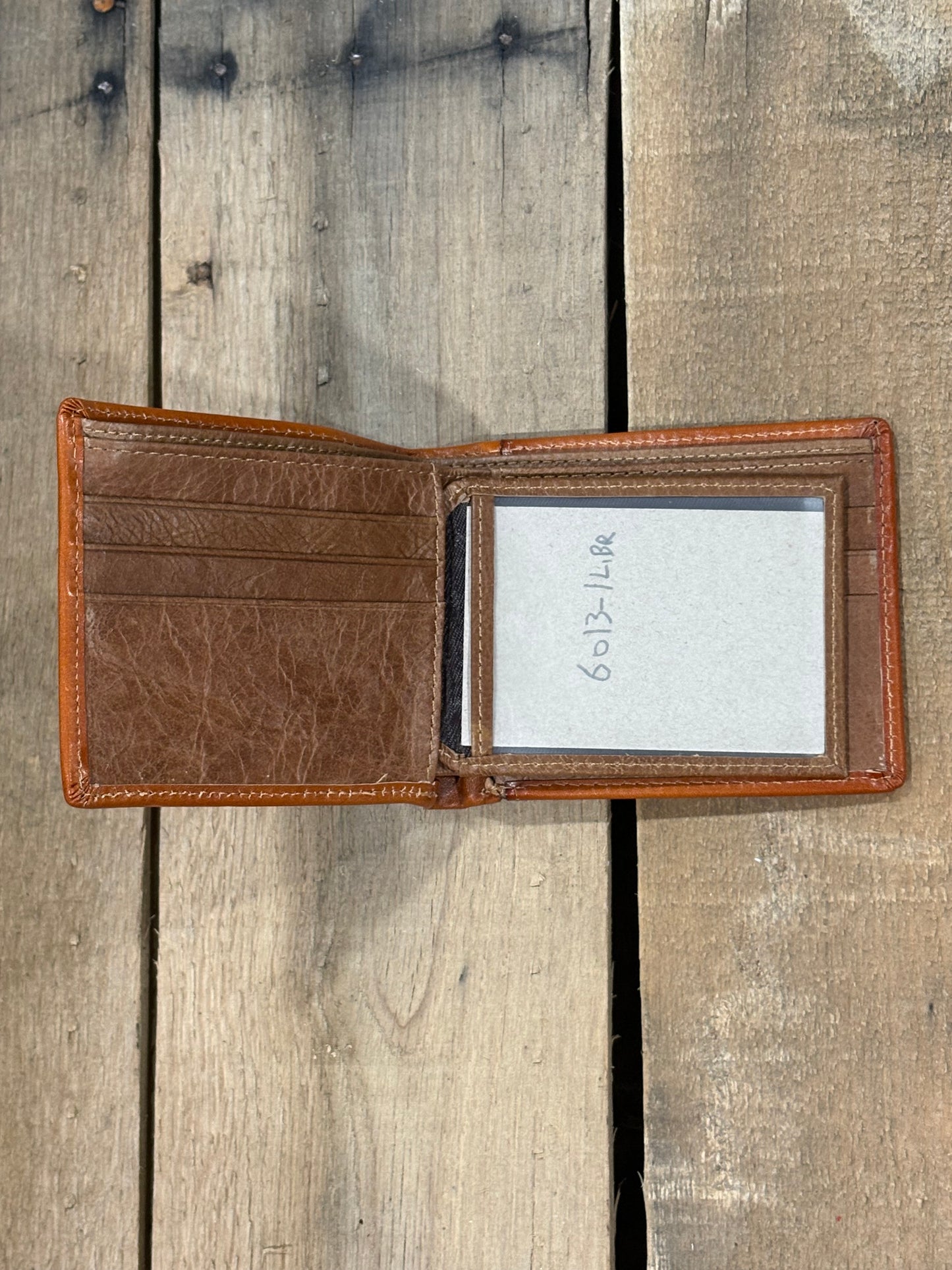 Light Brown leather wallet with three card slots and one ID window slot on a wooden surface