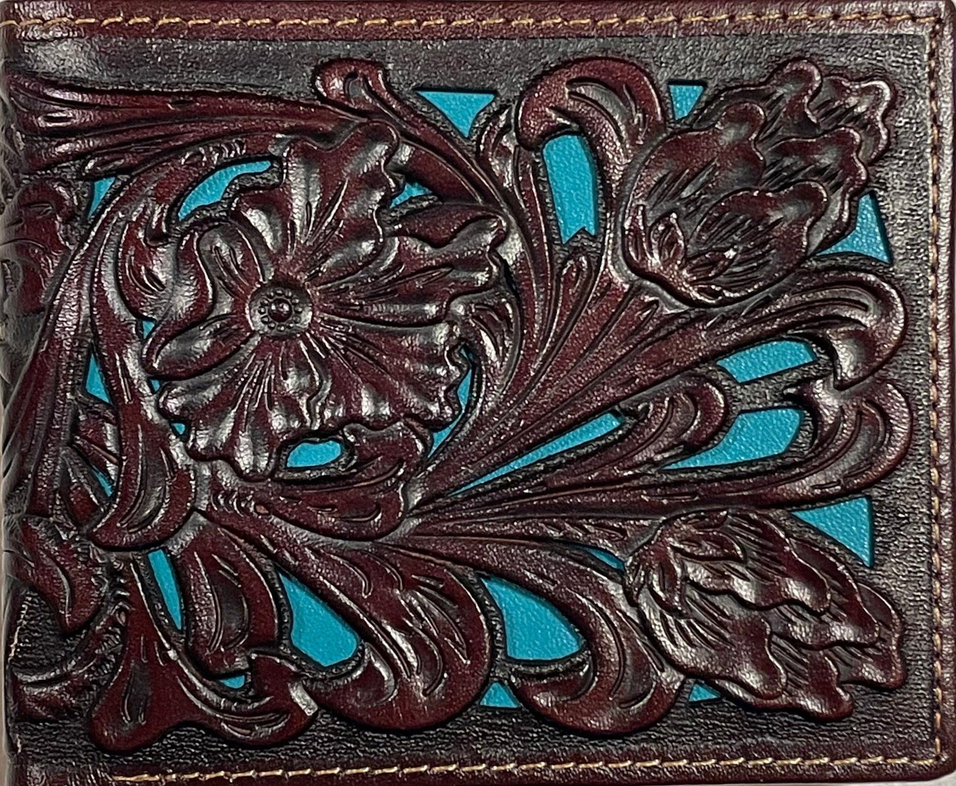 Close up of a Decorative leather wallet with intricate floral patterns on a turquoise background
