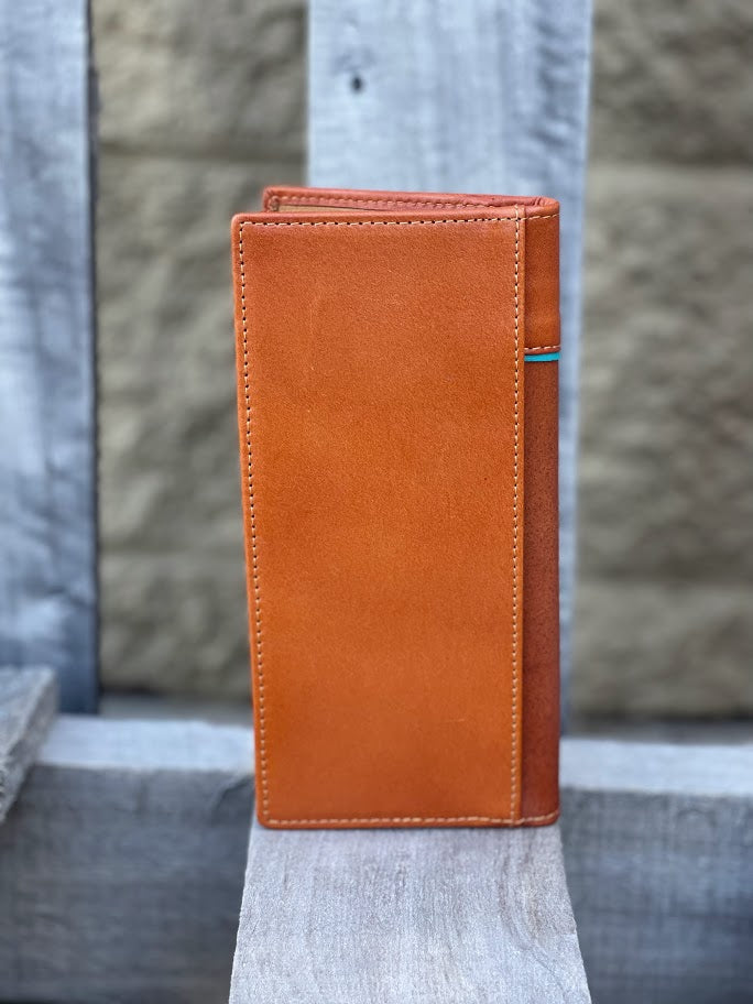 Light Brown leather wallet on a wooden surface with a blurred concrete wall background