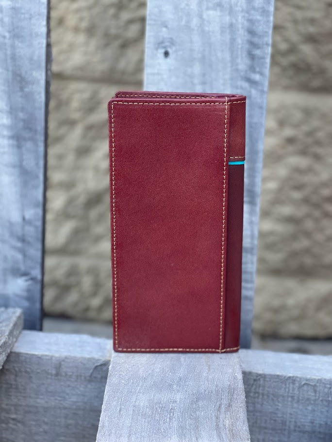 Brown leather wallet on a wooden surface with a stone wall background