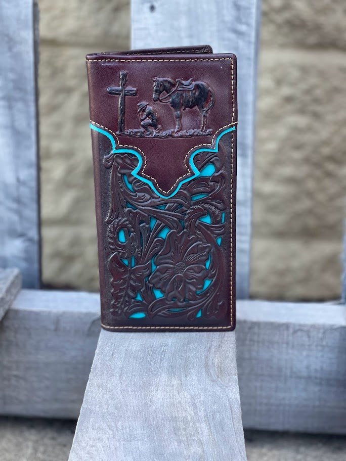 Coffee Brown leather wallet with Praying Cowboy intricate designs and blue accents on a wood surface.
