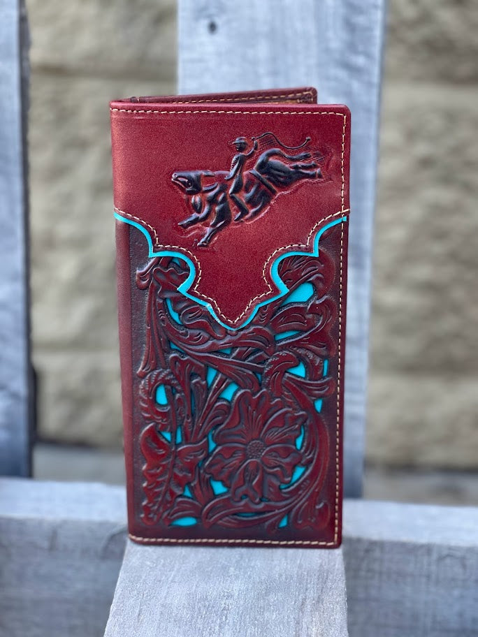 Brown leather wallet with bull rider intricate designs and a bull rider emblem on a wooden surface.