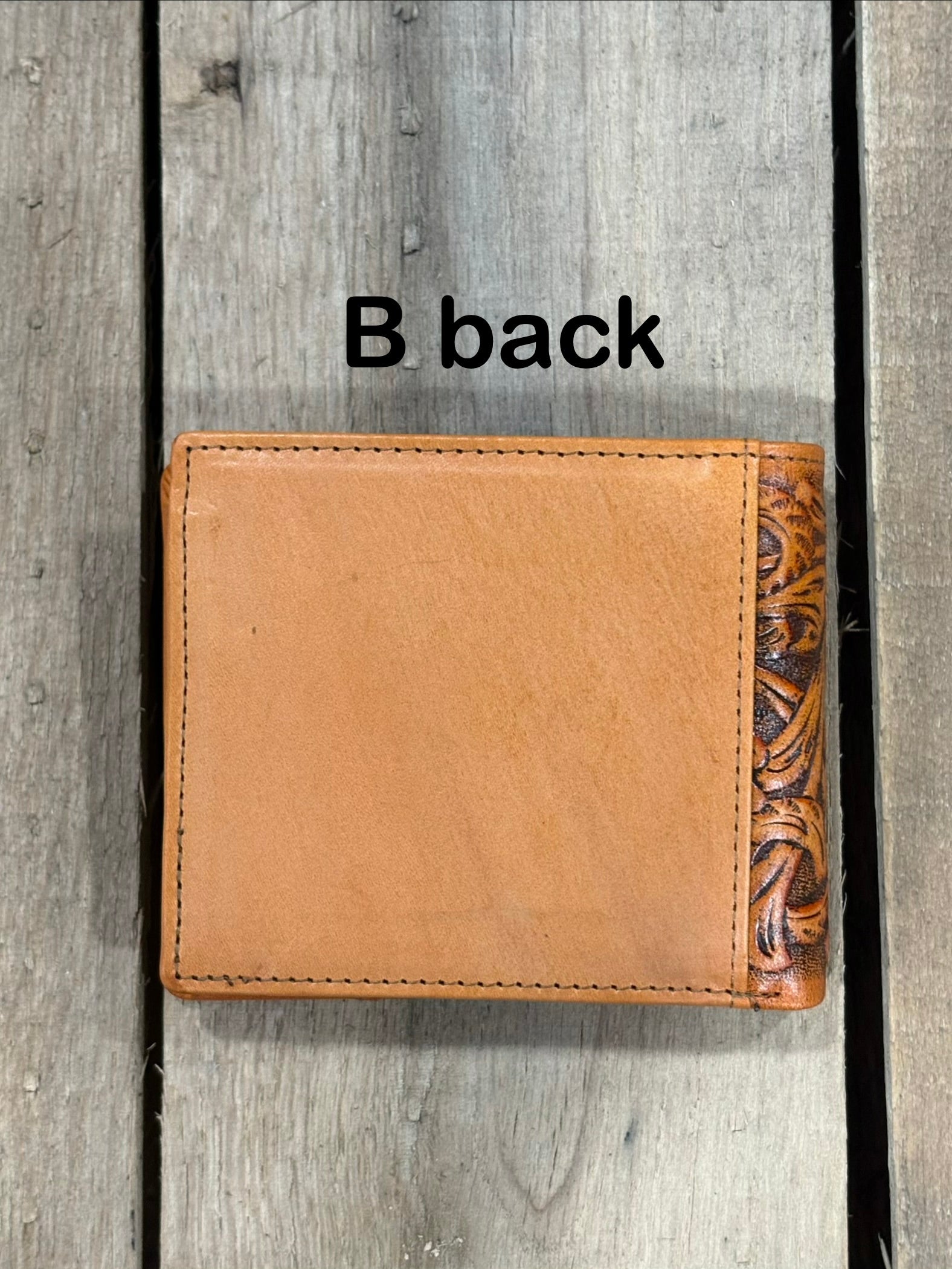Light Brown leather wallet with floral patterns on a wooden surface