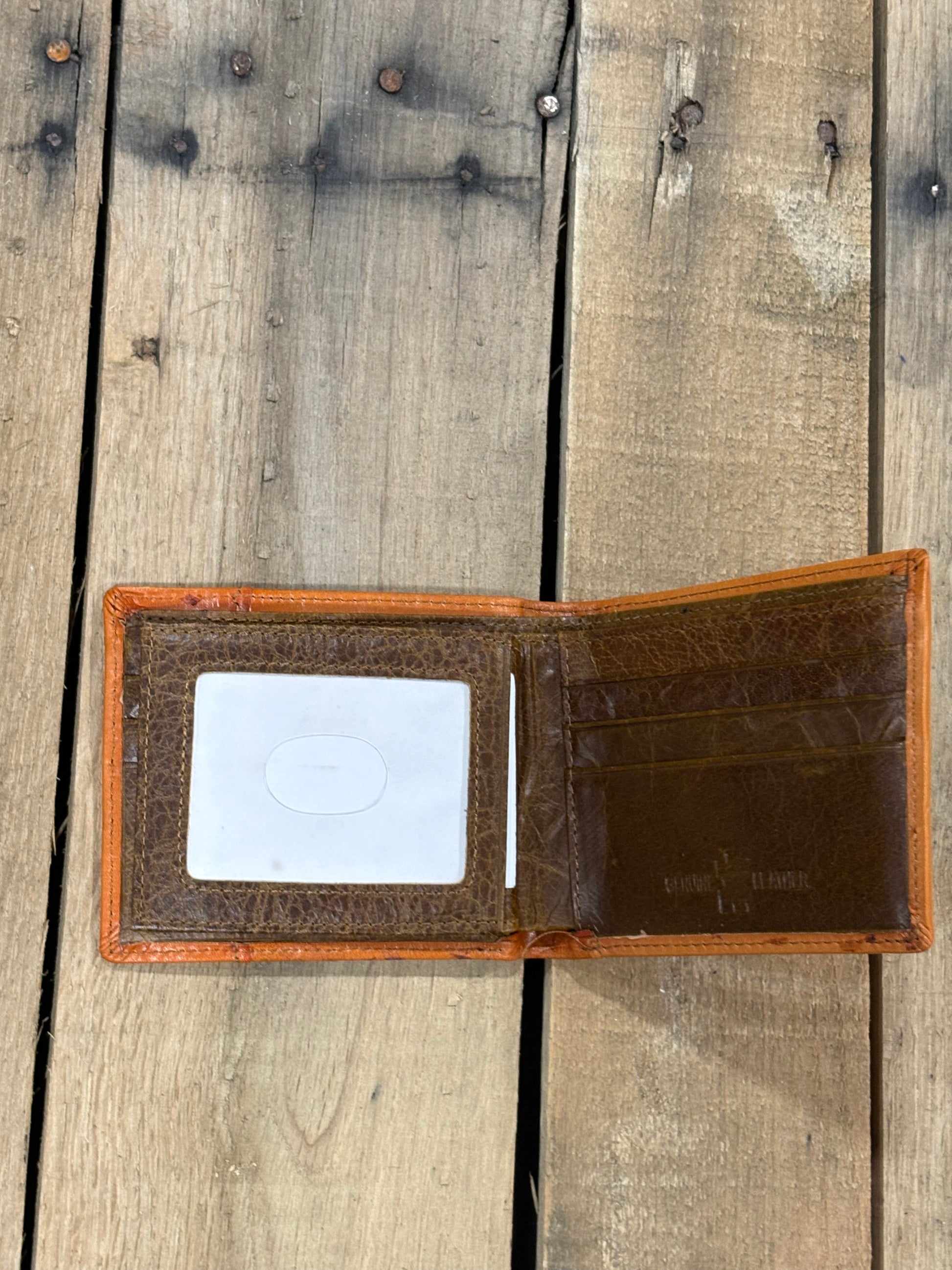 Brown leather wallet with a ID window slot and 3 card slots on a wooden surface